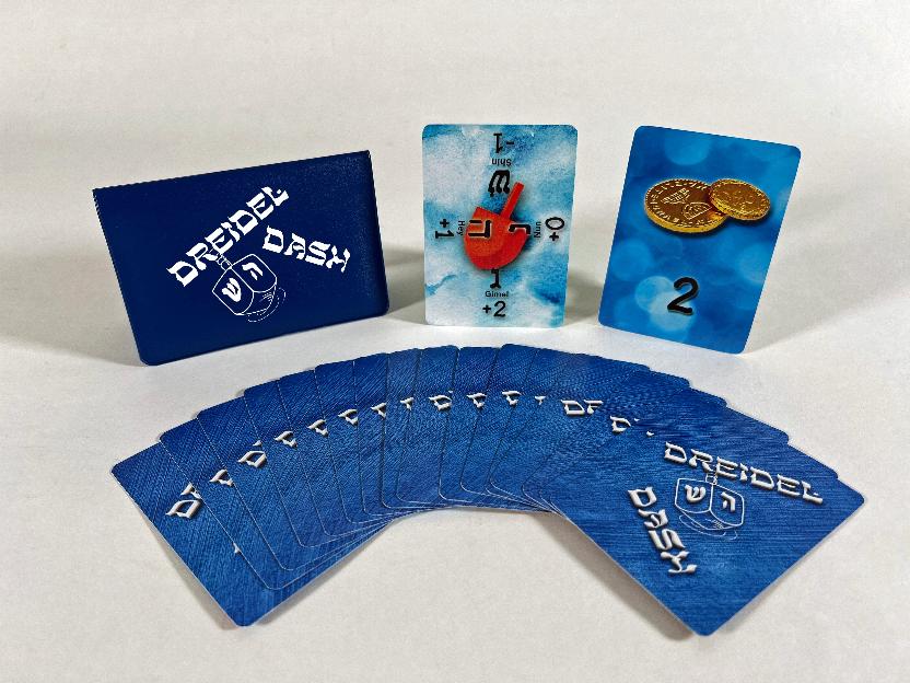 Cards laid out in a fan with the wallet, a dreidel card, and one gelt coin card standing up behind them.