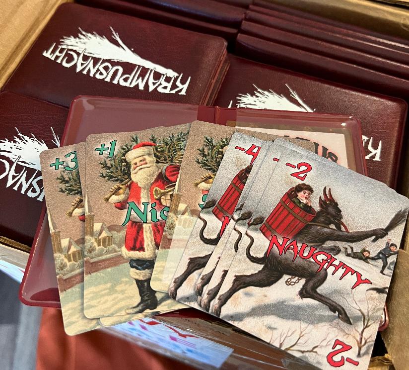 a box full of Krampusnacht games with one copy open and the cards fanned out on top.